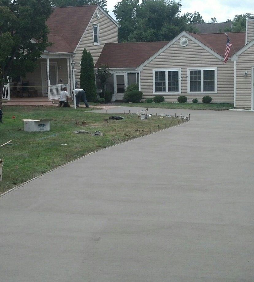 Newly poured curved concrete driveway leading to a two-story house