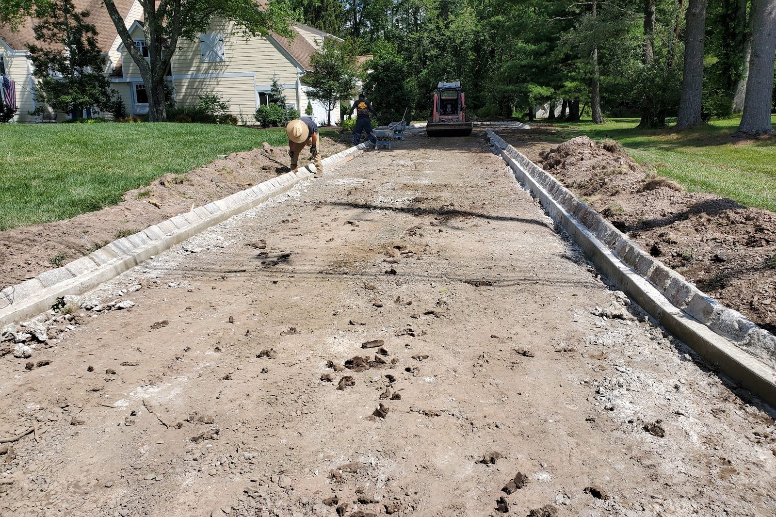 Long driveway excavated down to a dirt base with forms set along both edges