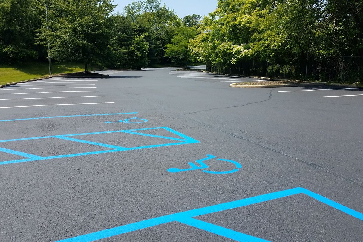 Bright blue accessible parking stall and access aisle striping on an asphalt lot