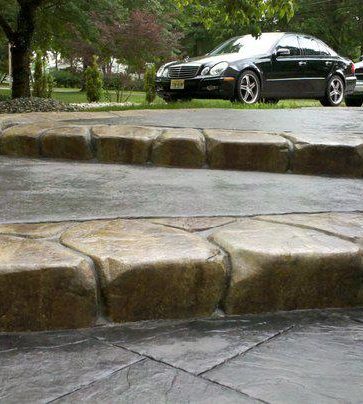 Close-up of stamped concrete steps with a textured stone-look edge, car parked in the background